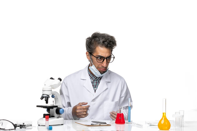 医学正面图穿着特殊白色西装的中年科学家围坐在桌子旁 拿着解决方案周围专业实验室