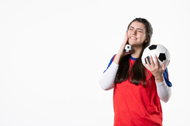 视图前视图穿着运动服的年轻女性 白色墙壁上有足球肖像前面微笑