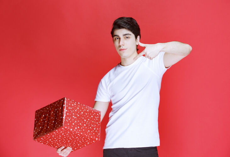 成人男人拿着一个红色的礼盒指着它模特年轻聪明