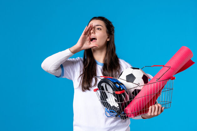 模型正面图会说话的年轻女性 带着装满运动用品的篮子前面肖像成人