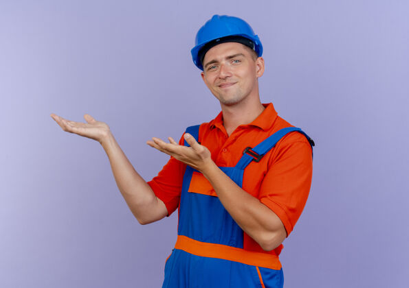 制服年轻的男建筑工人穿着制服 戴着安全帽 假装拿着紫色的东西年轻紫色请假装