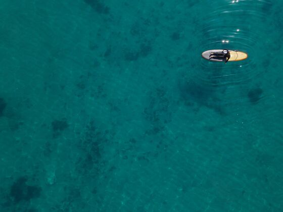 远射上图：男人躺在冲浪板上海洋水平季节