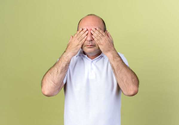 男人成熟的男人用手遮住眼睛隔离在橄榄绿的墙上成熟掩护手势