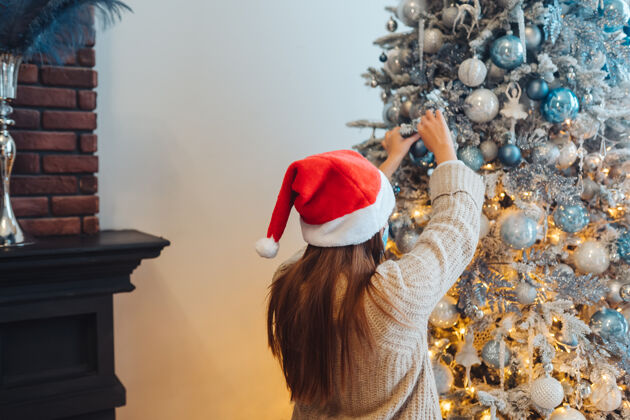 圣诞老人一个年轻的女人在装饰圣诞树女人准备留在家里
