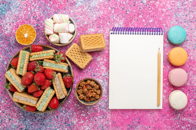 庆典美味的华夫饼干俯视图 粉色表面有马卡龙和新鲜的红色草莓饼干麦卡龙糖果