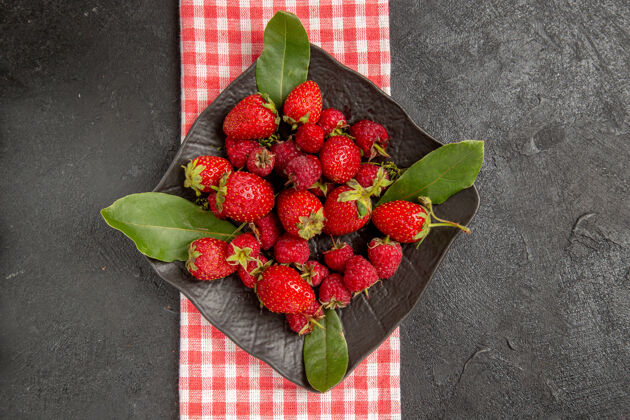 灌木顶视图新鲜的红色草莓在盘子里放在深色的桌子上 颜色是浆果和覆盆子覆盆子新鲜的红色草莓颜色
