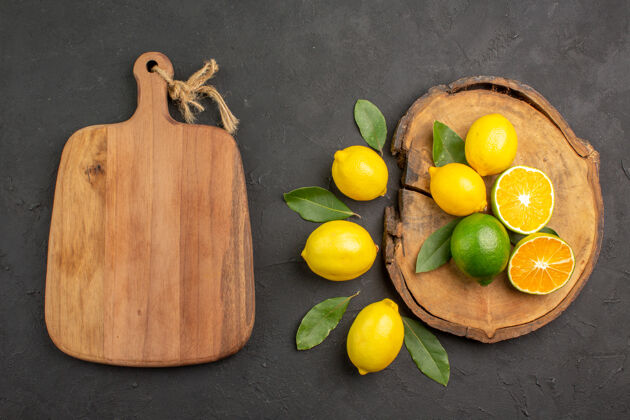 酸橙顶视图新鲜的酸柠檬和叶子放在深色的桌子上黄色的水果莱姆柑橘柑橘水果顶部