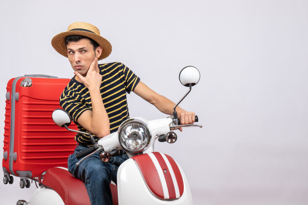 轻便摩托车前视图困惑的年轻人戴着草帽在轻便摩托车上看什么稻草人积极