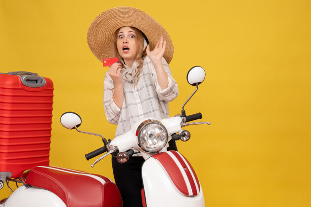 人俯视图：一个戴着帽子 坐在摩托车上拿着银行卡拿着行李的吓坏了的年轻女子摩托车帽子车辆