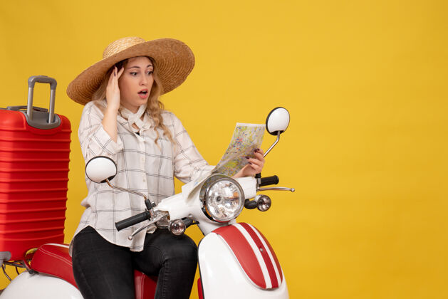人年轻女子戴着帽子 坐在摩托车上看地图 脸上泛着困惑的黄色压抑年轻女子坐比赛