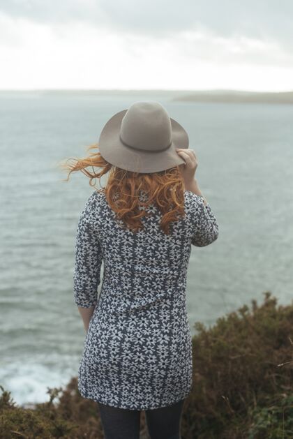 模特垂直拍摄一个戴着帽子的女人与大海海洋放松水