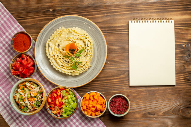用餐顶视图生面团-在棕色的桌子上放着蔬菜和调味品-生面团-生面团-生面团美食晚餐生的