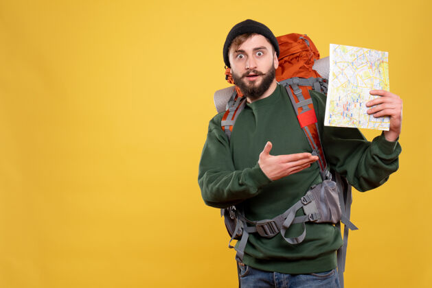 套装旅行概念与好奇的年轻人与背包和持有黄色地图人帅哥脸
