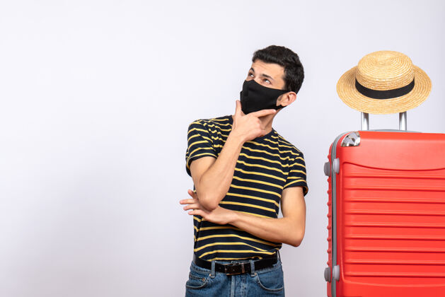 时尚正面图：站在红色手提箱旁的戴着黑色面具的年轻游客激动不已站立头发成人