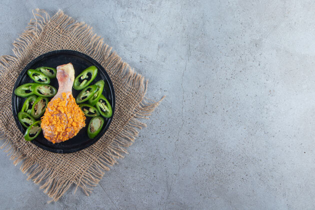 美味把腌好的鸡腿和胡椒片放在盘子里 放在粗麻布餐巾上 放在大理石背景上新鲜菜肴家禽