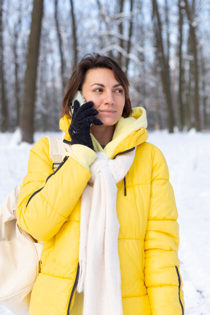 乐趣心情愉快的快乐女人漫步在雪域的冬日森林里 愉快地聊着电话 享受着公园里的户外时光霜冻森林人