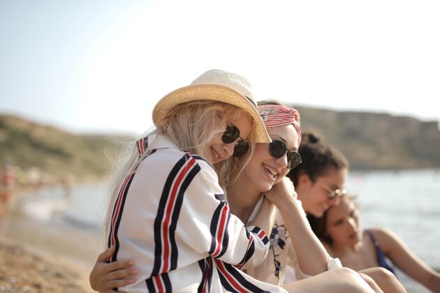 聪明两个年轻女子坐在沙滩上互相拥抱的选择性聚焦镜头漂亮女人沙滩