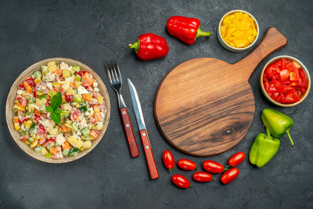 午餐一碗沙拉的顶视图 深灰色背景上有盘架餐具和蔬菜深色晚餐美味