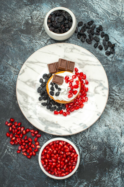 围嘴顶视图美味的奶油蛋糕与巧克力石榴和葡萄干浅黑色的背景陶瓷器皿背景薯片