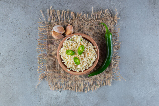 面食一碗面条旁边的胡椒和大蒜在粗麻布上 大理石背景上烹饪美味亚洲菜
