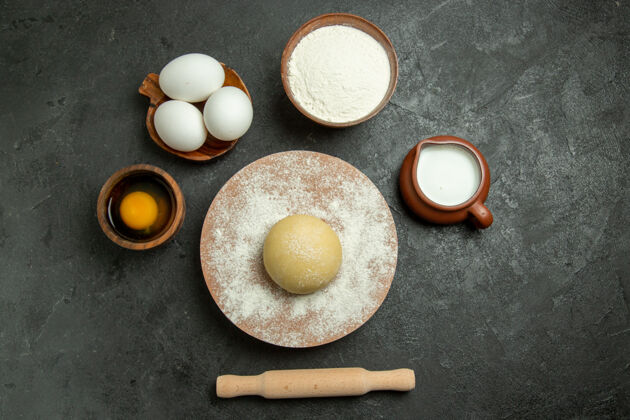 餐顶视图生圆形面团与鸡蛋和面粉的灰色背景食品面团面粉鸡蛋封闭的容器