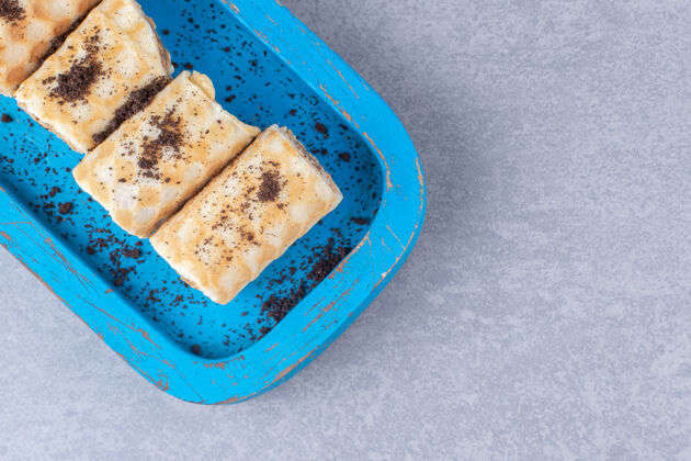 早餐巧克力华夫饼卷放在大理石上的蓝色盘子里美味烘焙食品甜点