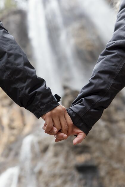 瀑布自然中的情侣手拉手近距离旅游探索牵手