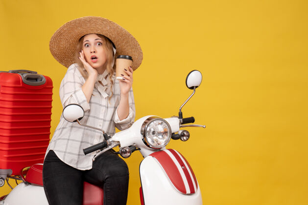 摩托车俯视图中惊讶的年轻女子戴着帽子 坐在摩托车上拿着咖啡足球年轻女子咖啡