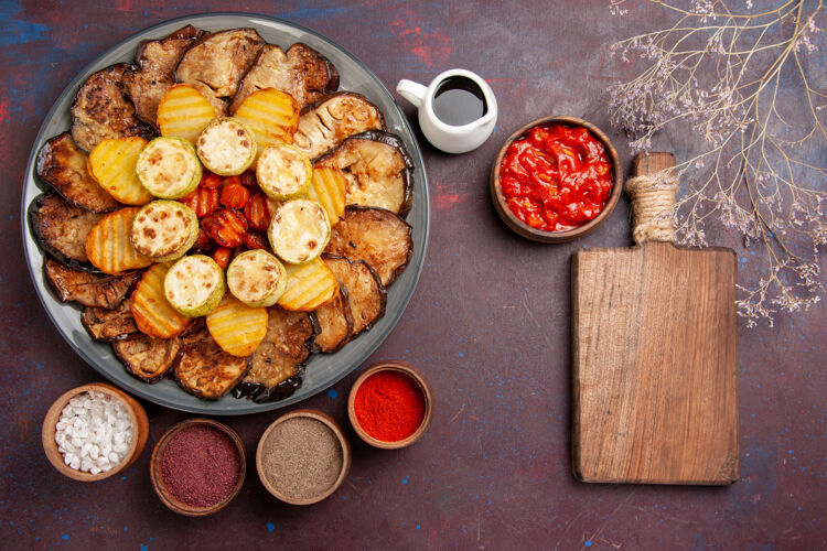 晚餐顶视图烤蔬菜土豆和茄子与不同的调味品在一个黑暗的桌子上蔬菜烤箱土豆