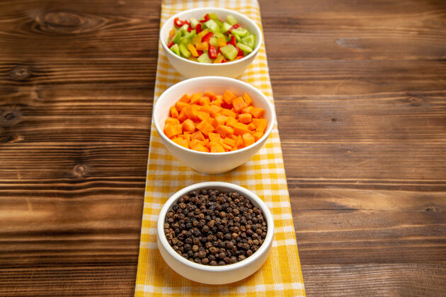 胡椒正面图棕色木桌上不同调味料的甜椒切片蔬菜餐食品健康沙拉饭切片前面