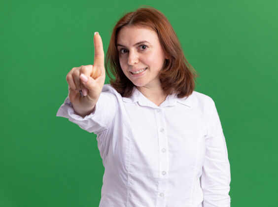 女人身穿白衬衫的年轻女子面带微笑地看着前面 第一个站在绿色的墙上衬衫年轻站立