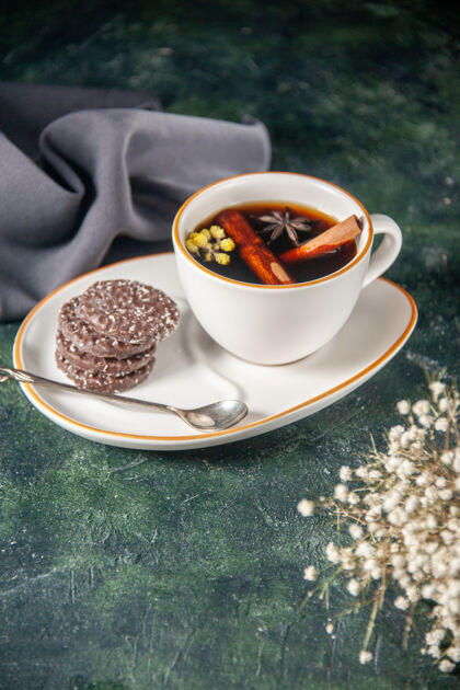 杯子前视图一杯茶加上甜巧克力饼干在盘子和托盘的深色表面上仪式玻璃甜早餐糖蛋糕的颜色盘子前面巧克力
