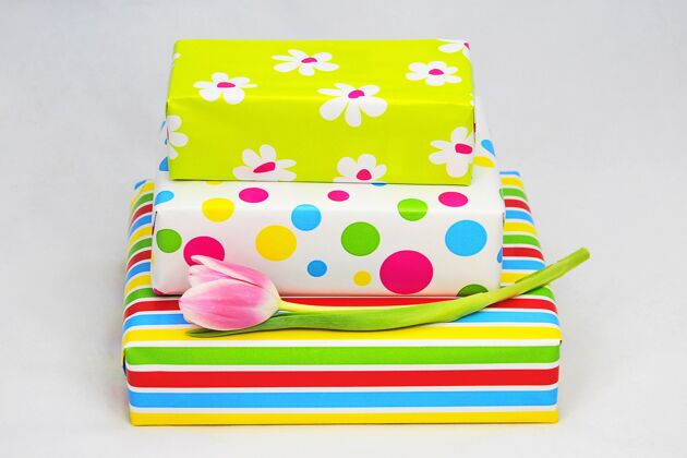 礼物特写镜头的包装彩色礼品盒和郁金香上的白色表面生日蝴蝶结配件
