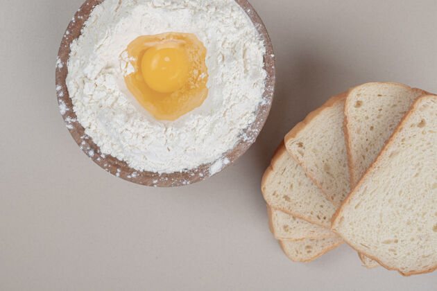 面粉新鲜的切片白面包和装满面粉的木碗美味食物蛋黄