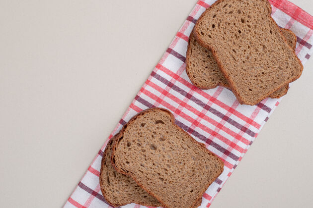 脆把新鲜的棕色面包片放在桌布上谷类新鲜美食