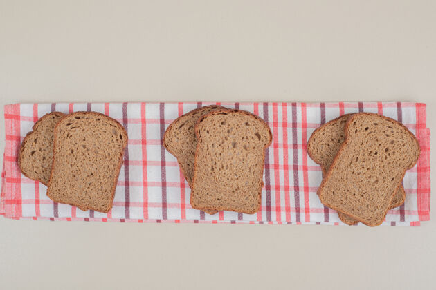 面包把新鲜的棕色面包片放在桌布上食品营养谷类