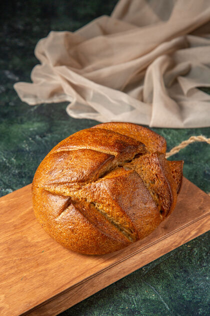 整个整个新鲜黑面包的俯视图 在深色表面的棕色木砧板上面包房木板切