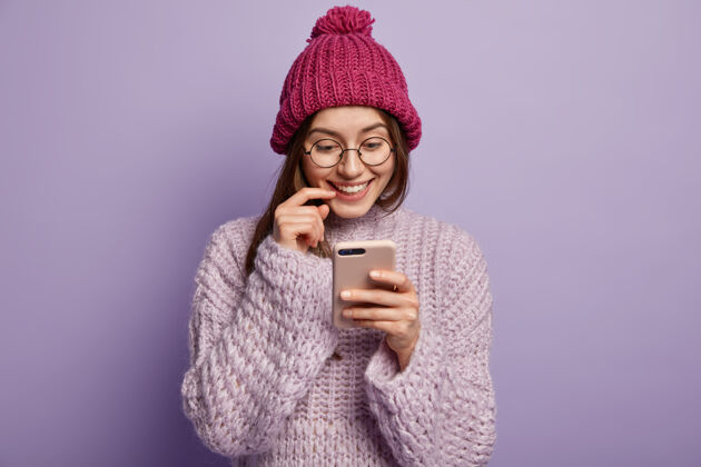 人年轻的黑发女人穿着舒适的冬装拿着电话帽子电话年轻人