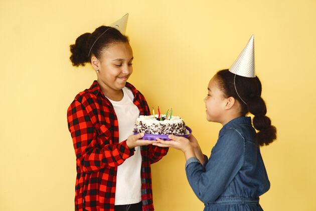 美国小女孩的生日被隔离在黄色的墙上孩子们拿着蛋糕人女性二