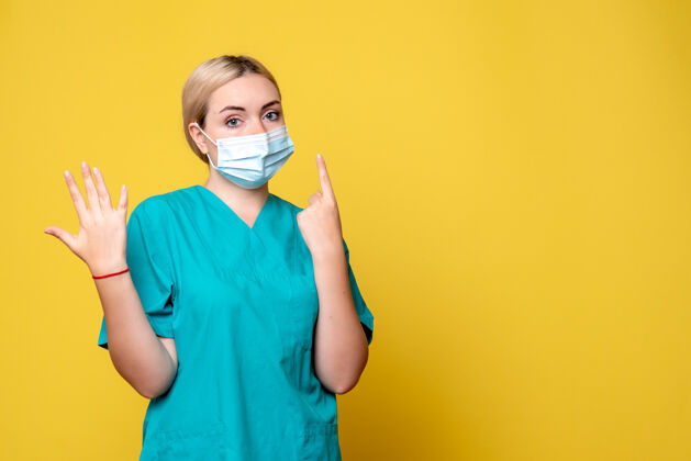 脸黄色墙壁上穿着医用衬衫和无菌口罩的年轻女医生的正面图漂亮医院绝育