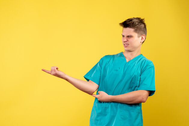 男人黄色墙壁上穿着医疗服的男医生的正视图病毒健康套装