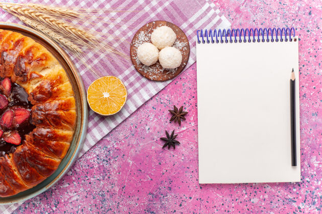 干的俯瞰美味的草莓馅饼圆形水果蛋糕上的粉红色椰子笔记本蛋糕