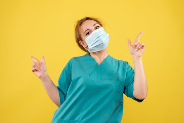 面罩黄墙上穿着医疗服 戴着无菌口罩的女医生的正面图医疗绝育女医生