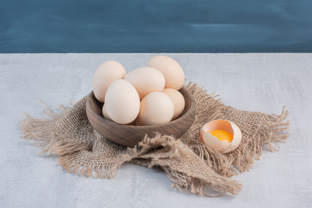 鸡蛋在大理石桌上的一块布上 蛋黄旁边放一碗鸡蛋味道早餐营养