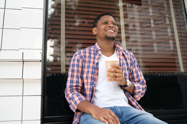 人坐在咖啡店外喝咖啡的非裔美国人城市概念外卖休闲城市