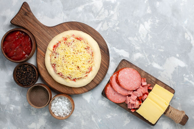 小吃在浅白的桌子上俯瞰生比萨饼 上面有奶酪和不同的调味品食物健康美味