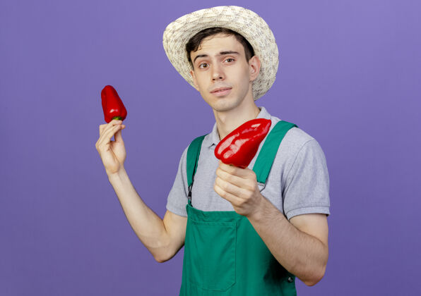 胡椒自信的年轻男园丁戴着园艺帽捧着红辣椒信心花园园艺