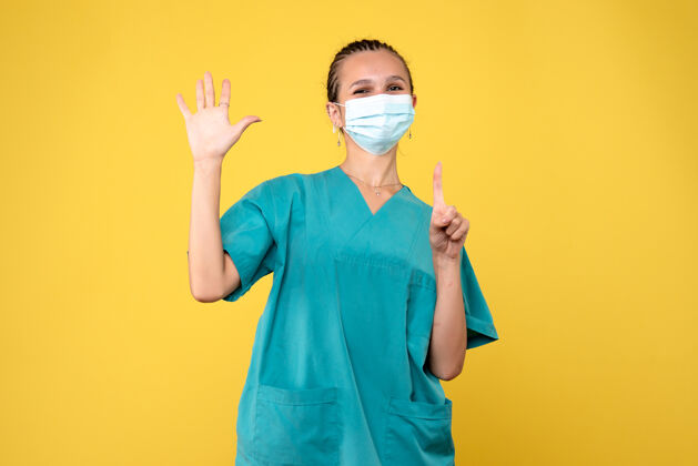 绝育黄墙上穿着医疗服 戴着无菌口罩的女医生的正面图正面护士女医生