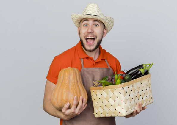 男兴奋的男园丁戴着园艺帽 手里拿着南瓜和菜篮持有园艺篮子
