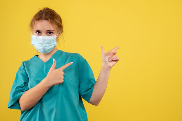 医疗黄色墙壁上戴着无菌防护面具的女医生的正视图医院护士肖像